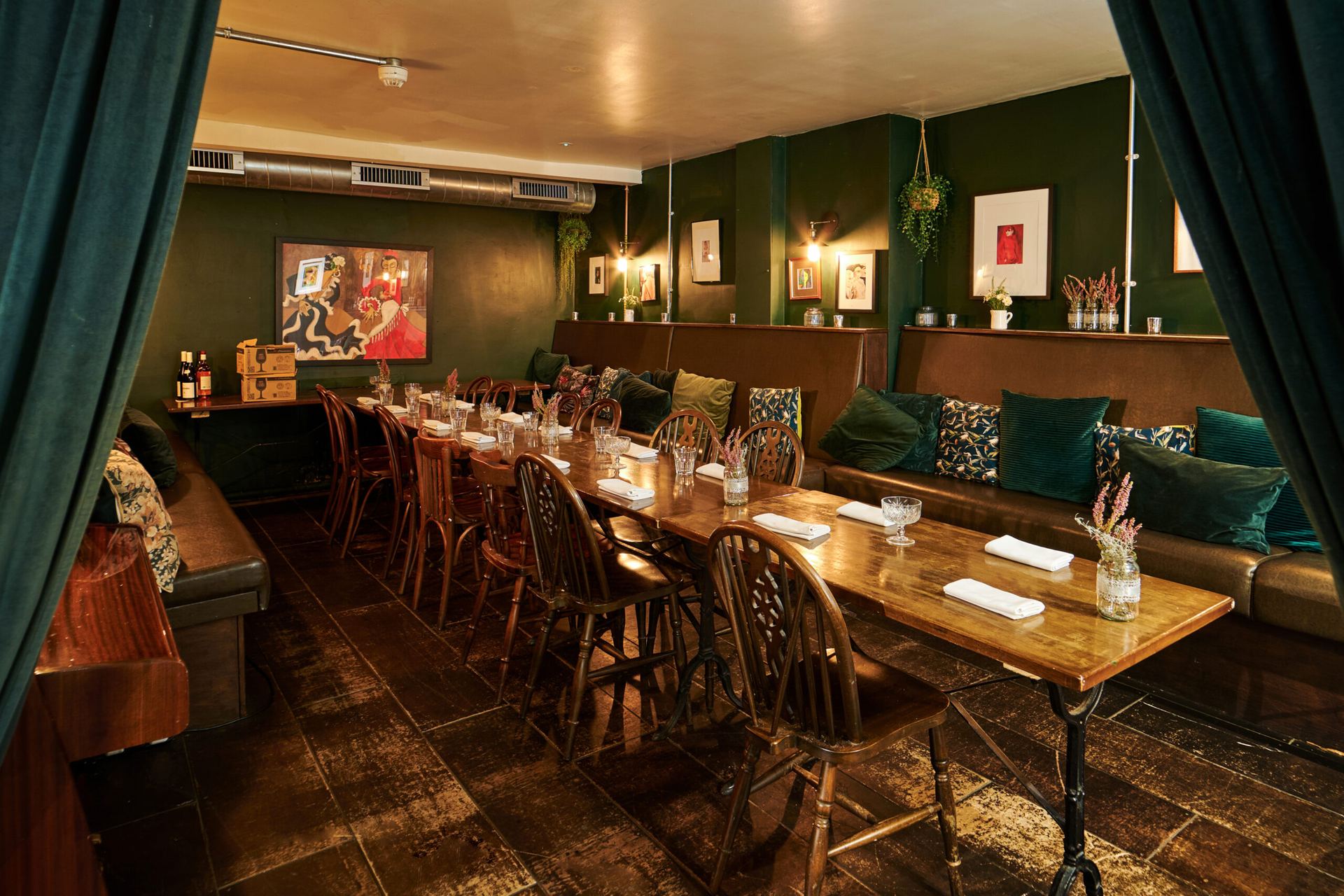 The long table in Queens' green private dining room, framed by velvet curtains