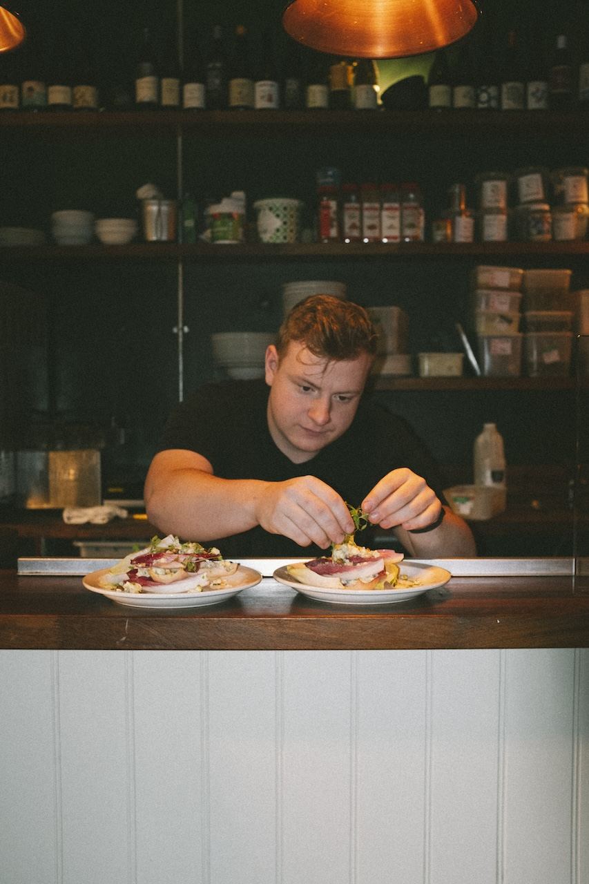 A member of the Queens kitchen finishing a dish